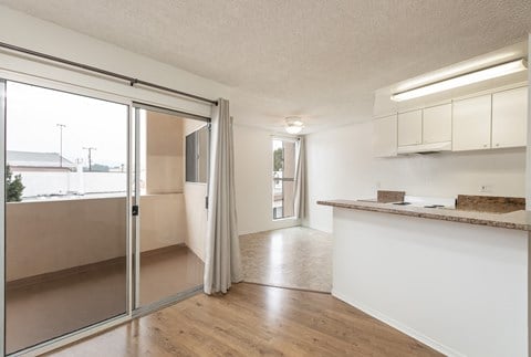 an open kitchen and living room with a sliding glass door to a balcony